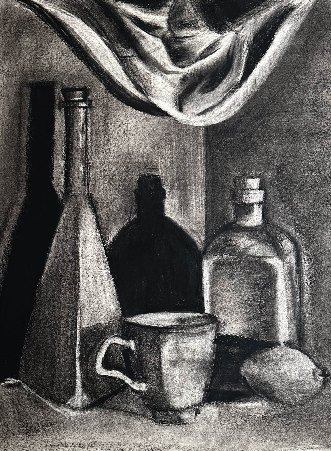Charcoal still life: drapery swagged across the top, a tall corked bottle at left and a stoppered flask at right, a mug and a lemon in front, and a large bottle-shaped cast shadow filling the centre