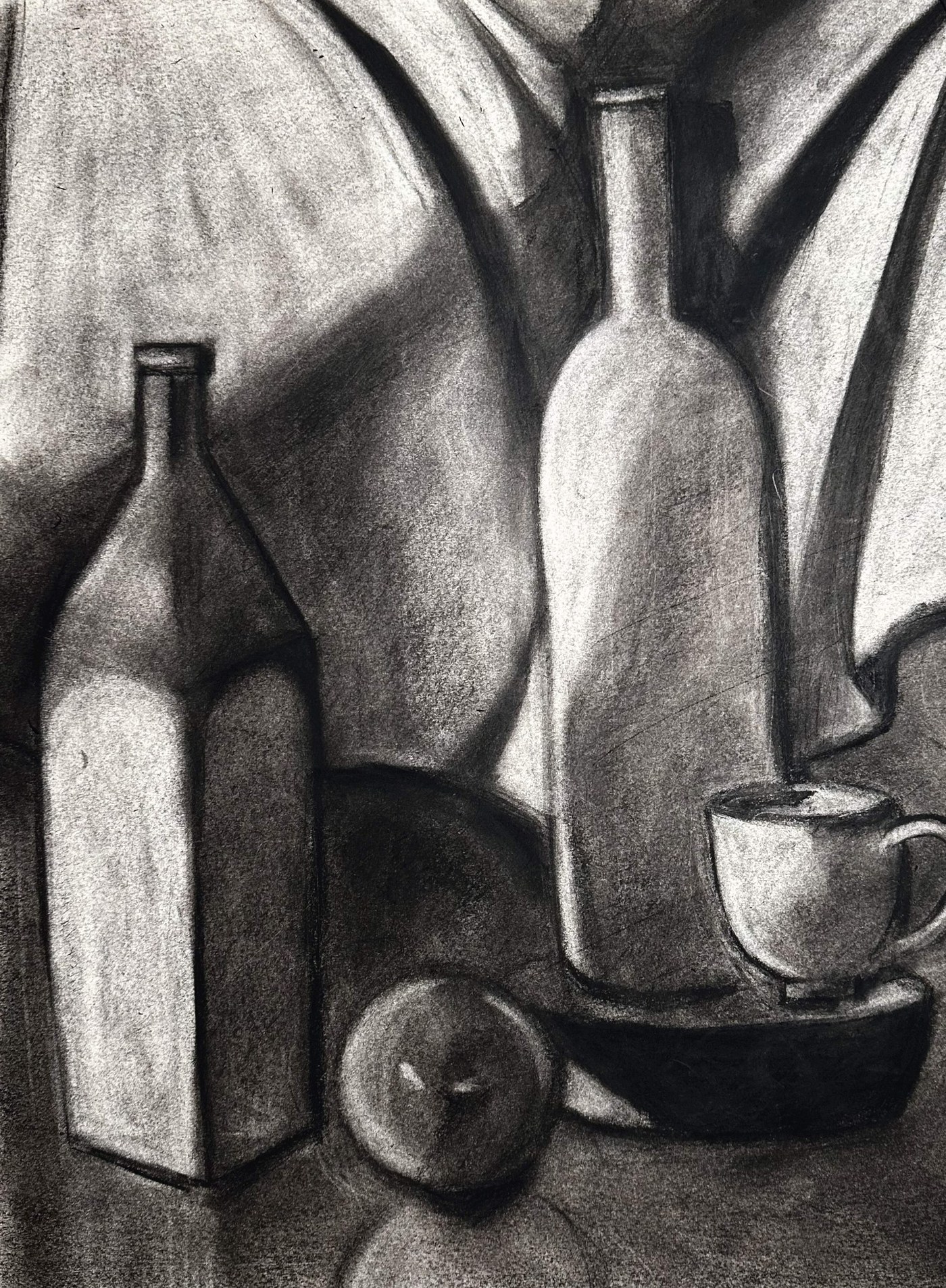 Charcoal still life: a faceted bottle and a round-shouldered bottle against folded cloth, with an apple, a teacup and a dark bowl