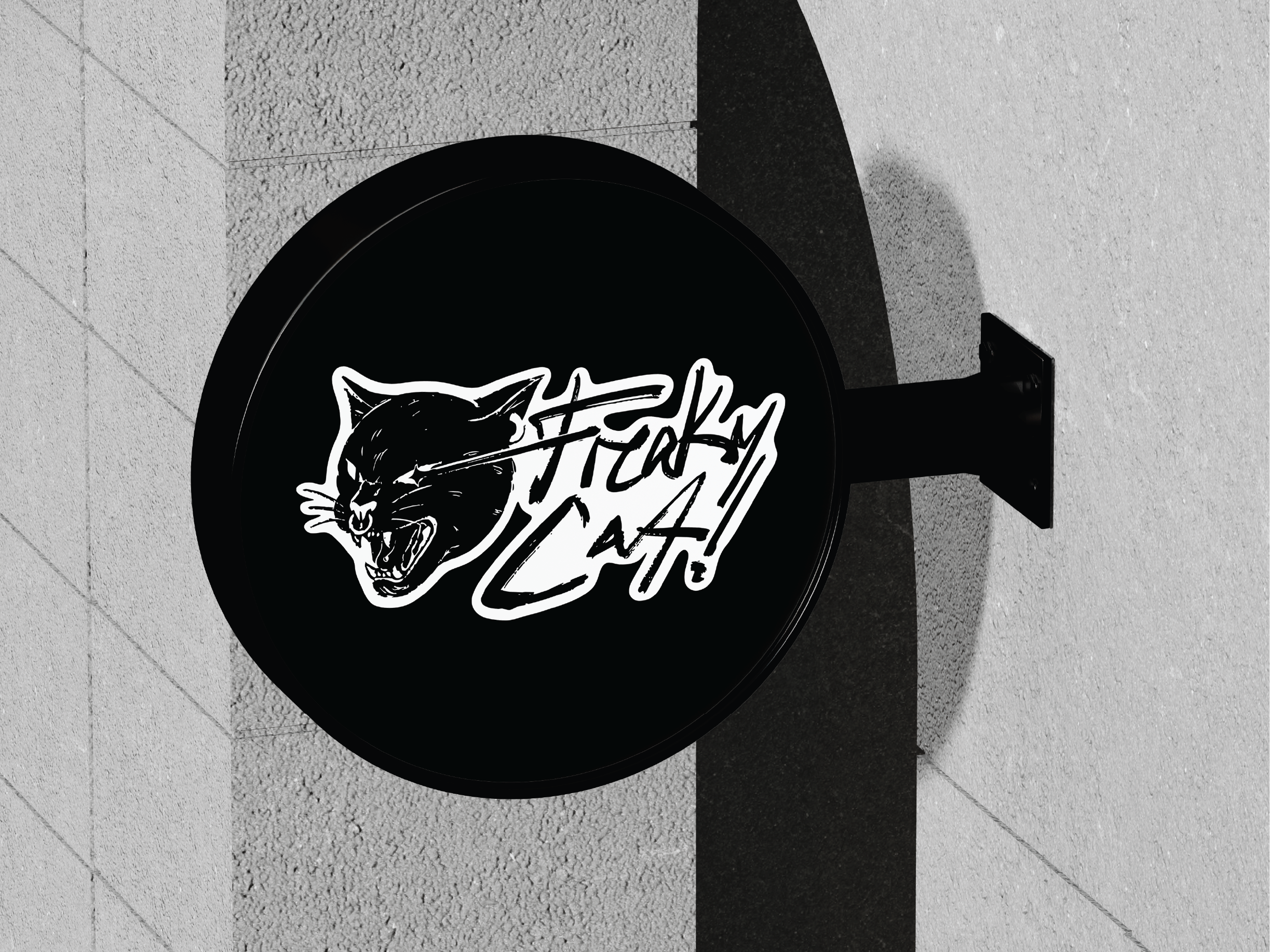 Round black projecting sign carrying the Freaky Cat! logo, mounted on a concrete wall