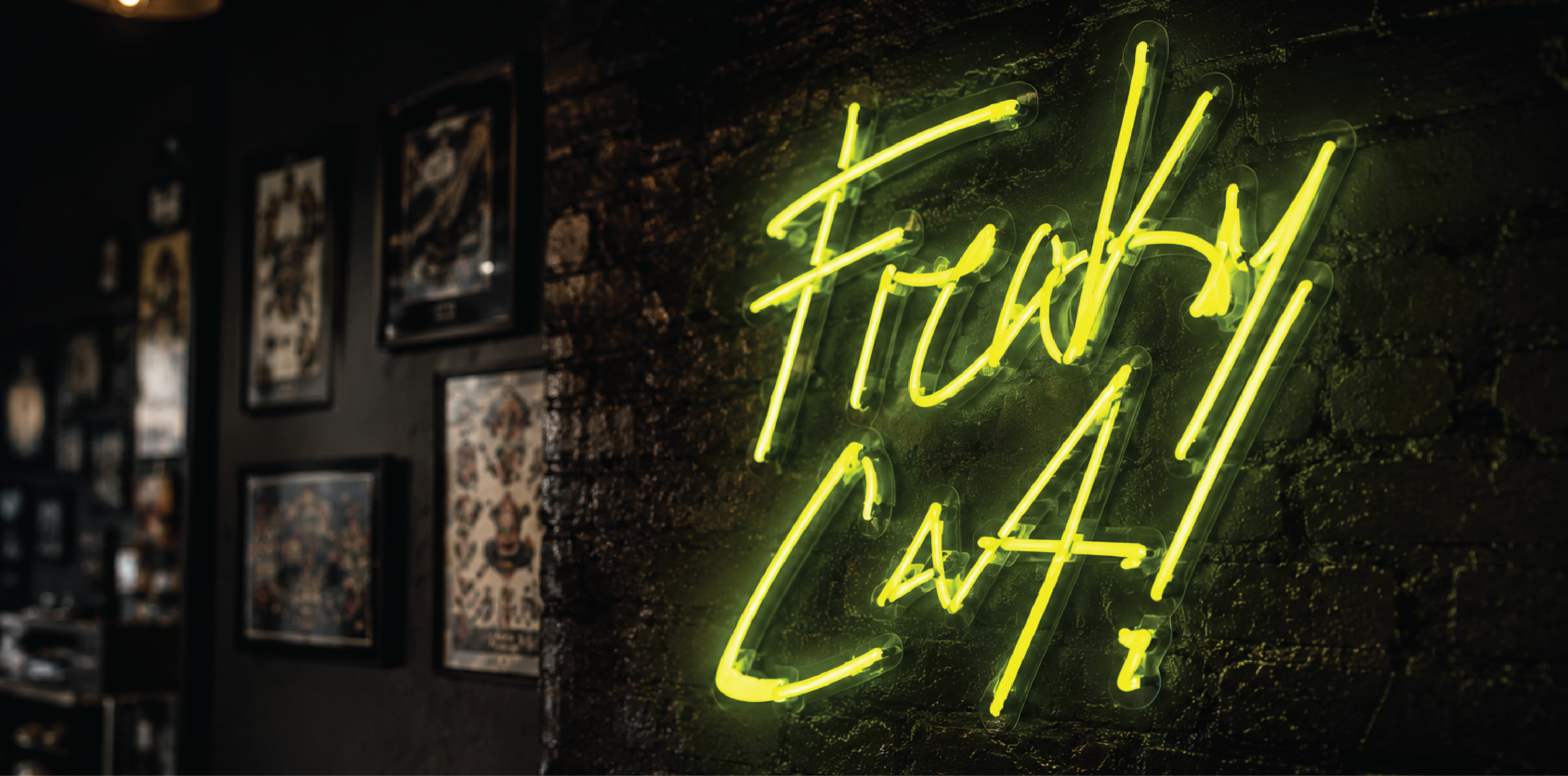 Freaky Cat! wordmark as a lime neon sign on a dark brick wall inside the shop