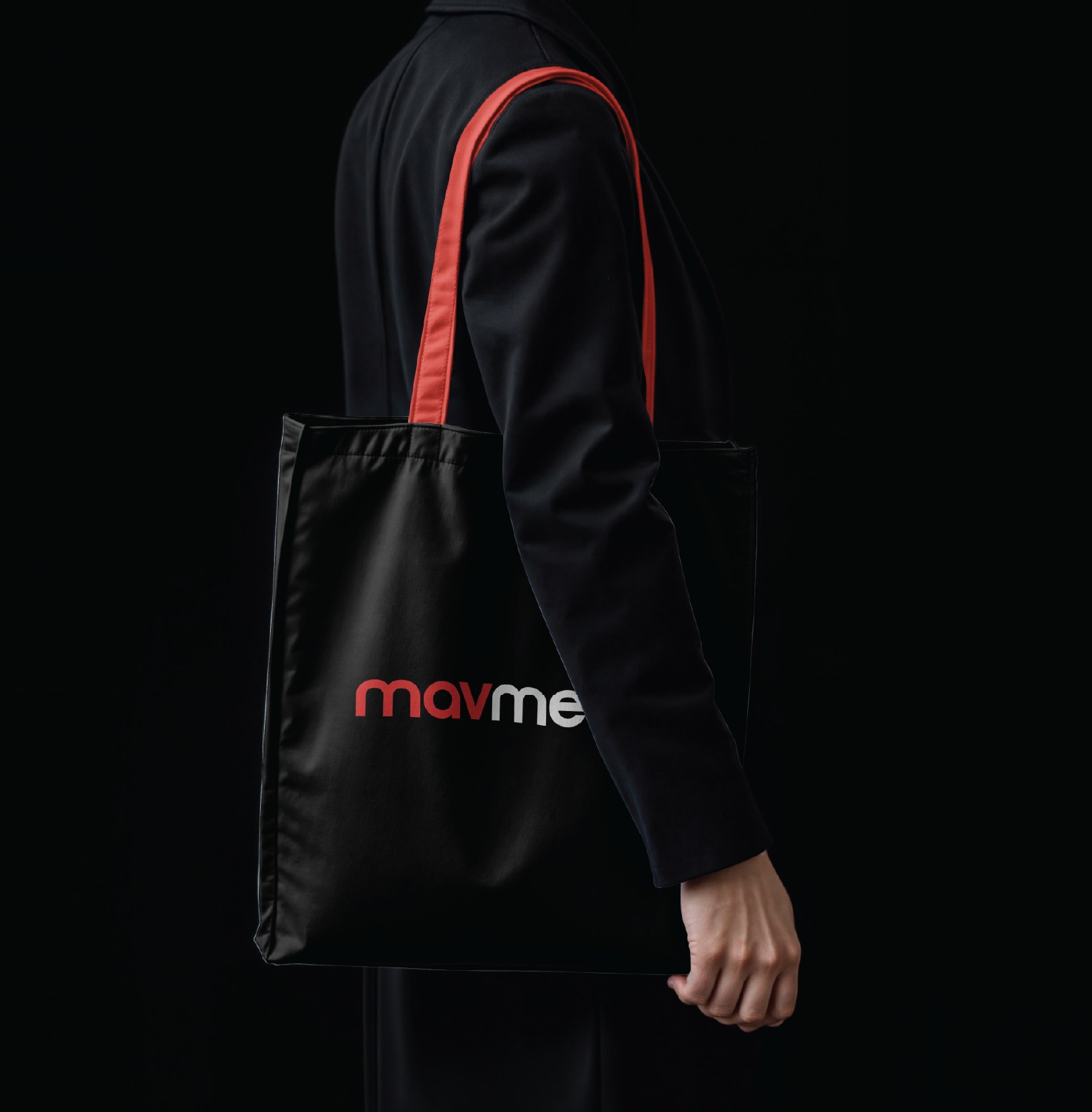 A person in black carrying the black Mavmedia tote by its red handle